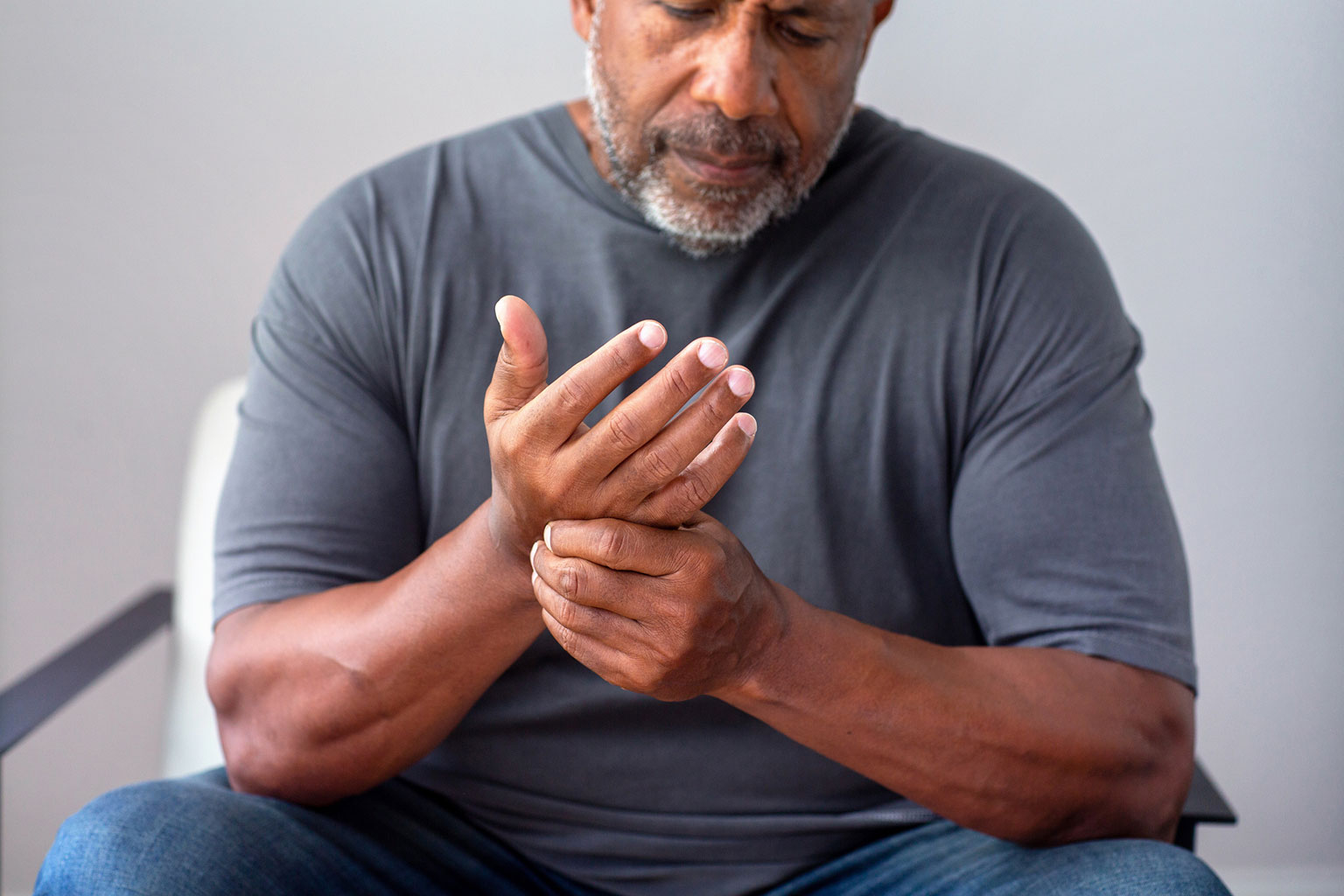 Man with nerve compression and nerve injury holding his right hand with his left hand