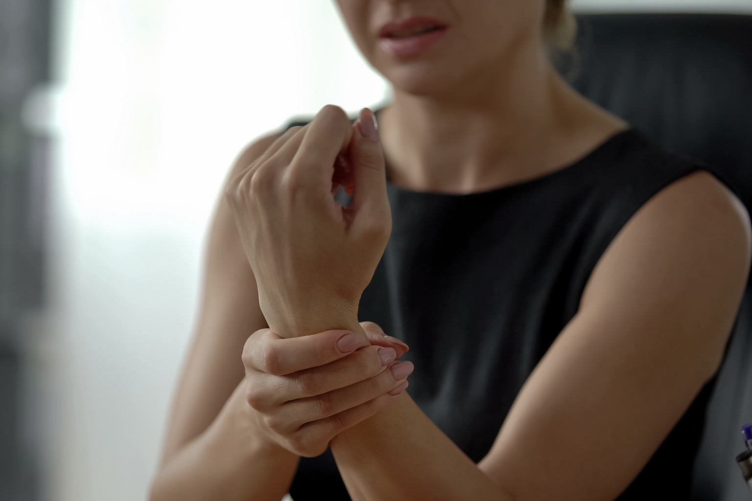 woman with a traumatic hand or wrist condition holding her left wrist with her right hand